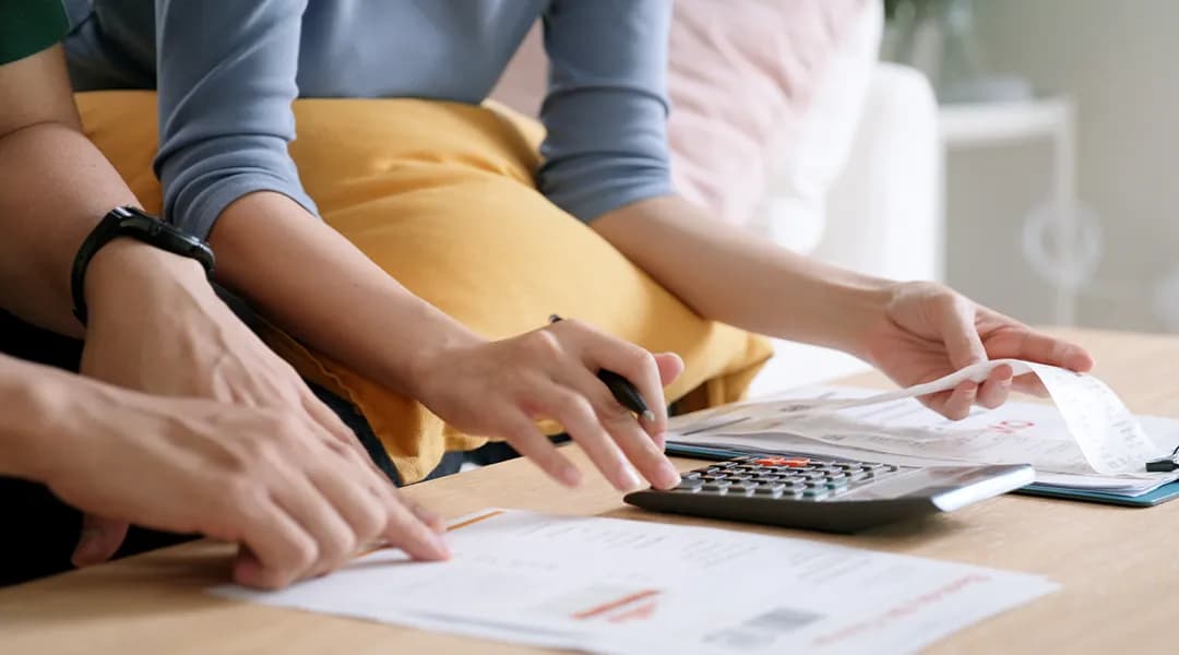 Un couple travaille sur un papier avec une calculatrice pour une demande de prêt.