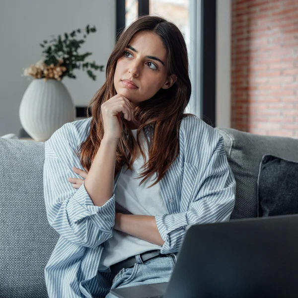 Femme assise sur un canapé, utilisant un ordinateur portable, illustrant le concept de cautionnement de prêt.