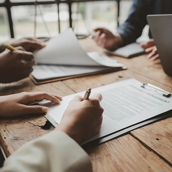 Hommes et femmes assis à une table avec des papiers et un ordinateur portable pour une demande de prêt.