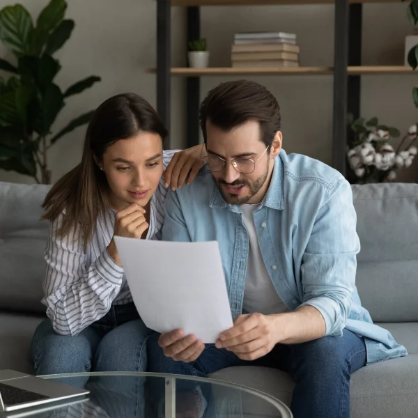 Un couple examine des documents sur un canapé, discutant de prêts sans vérification de crédit.